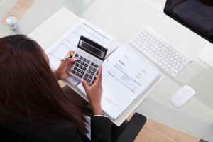 Confident Businesswoman Calculating Tax At Desk