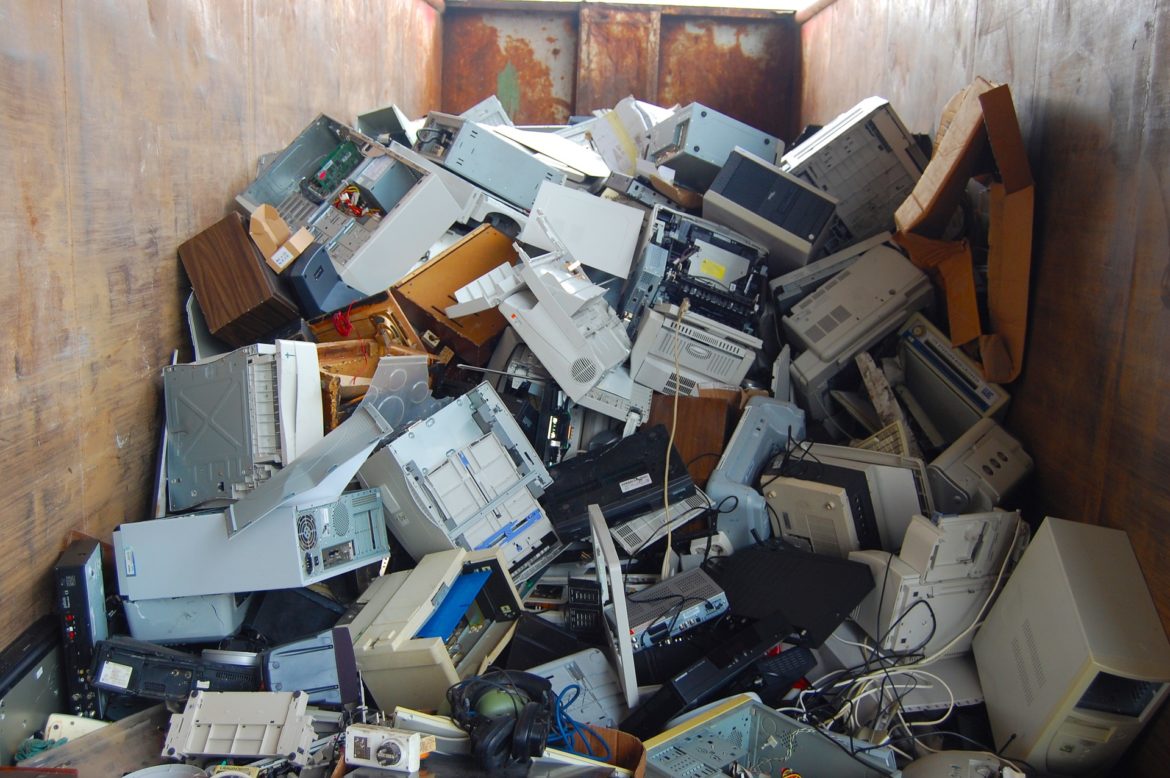 old office equipment sitting in a dumpster